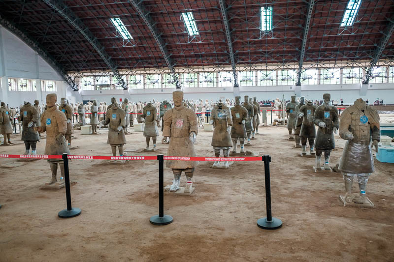 China-Xian-Terracotta Army - Some of them are covered in glad wrap. Many of them are put back together from pieces of broken pottery.