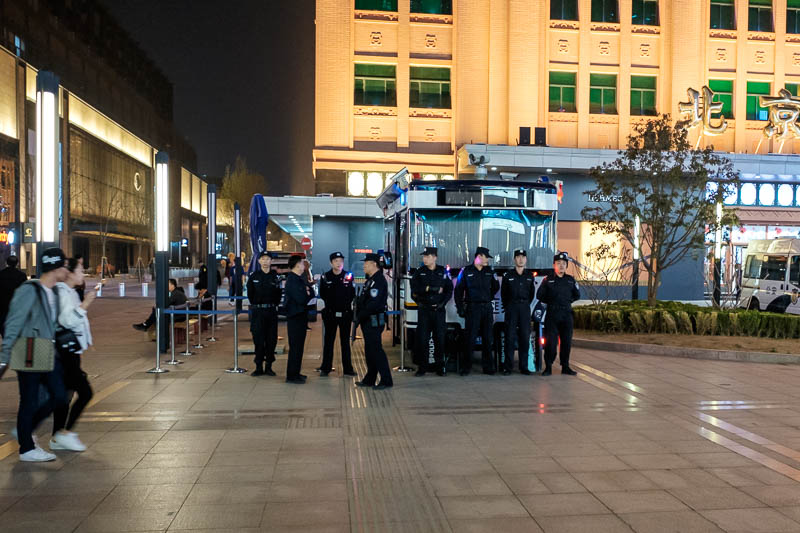 China-Beijing-Food-Wangfujing - The police are everywhere here. These guys are getting yelled at by their boss before they start their shift. Note they wear flashing red and blue lig