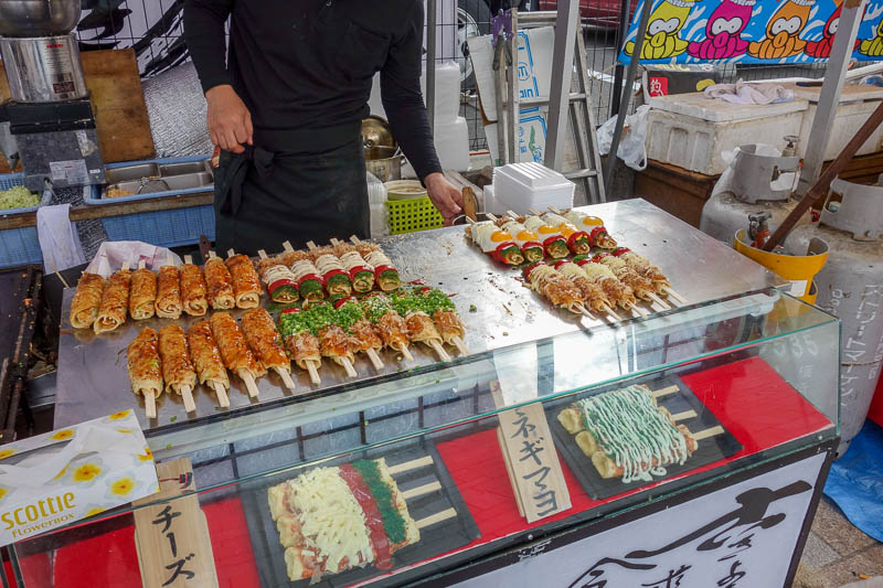 Japan 2015 - Tokyo - Nagoya - Hiroshima - Shimonoseki - Fukuoka - How the hell do you eat this? Its Okonomyaki on a stick. Look at the fried egg wrapped around it. Theres no way that would have the structural integri