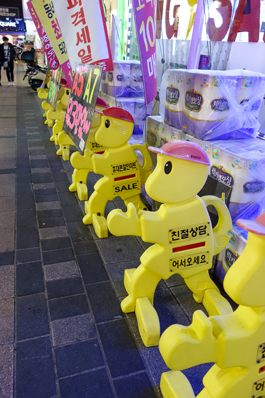 Korea-Busan-Neon-Beef-Department Store - Plastic yellow work men are doing good work all over Korea. Here they are particularly effective at guarding toilet paper.