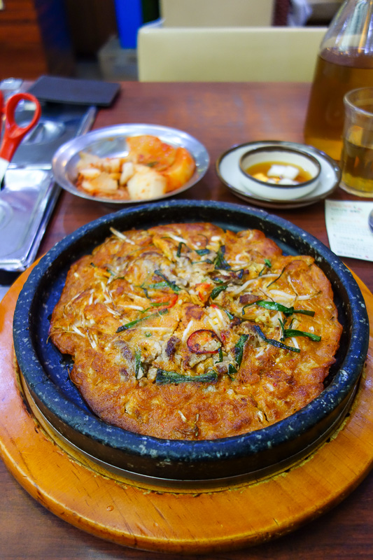 Korea again - Incheon - Daegu - Busan - Gwangju - Seoul - 2015 - At first glance you might find that to be a pizza. But its a kimchi pancake. Very good! I added lots of chilli flakes and pepper. Also this place prid