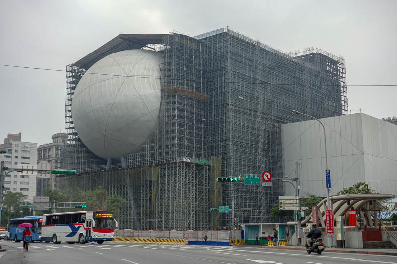 A full lap of Taiwan in March 2017 - Near the bus stop is this building under construction. Chinese people appreciate the spectacle of a giant windowless orb wedged into the side of a bui